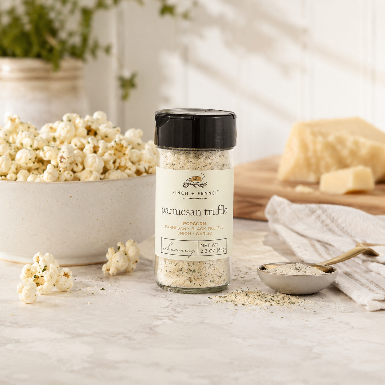 Jar of parmesan truffle seasoning on a table with popcorn and cheese in the background