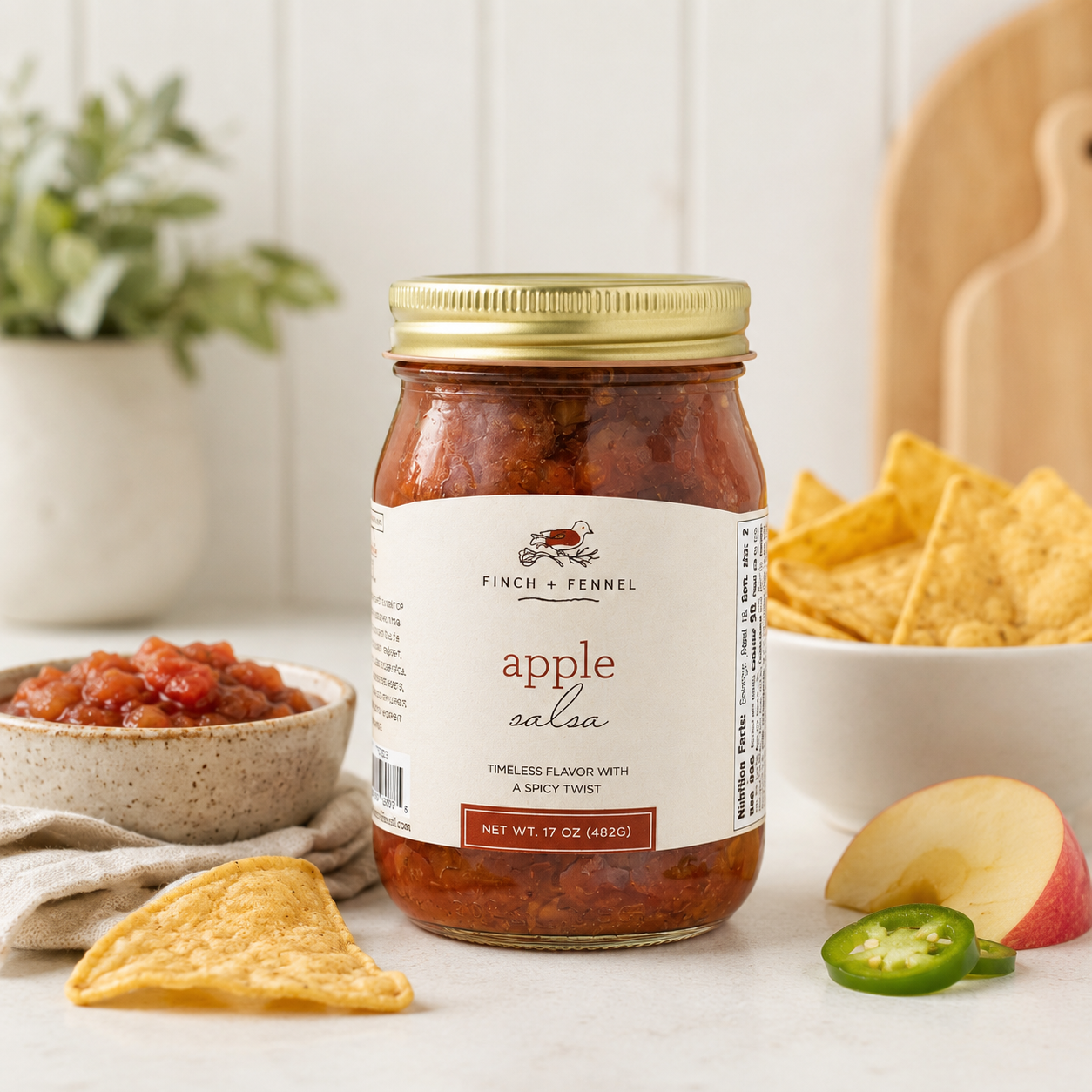 Jar of apple salsa with tortilla chips and salsa on a table