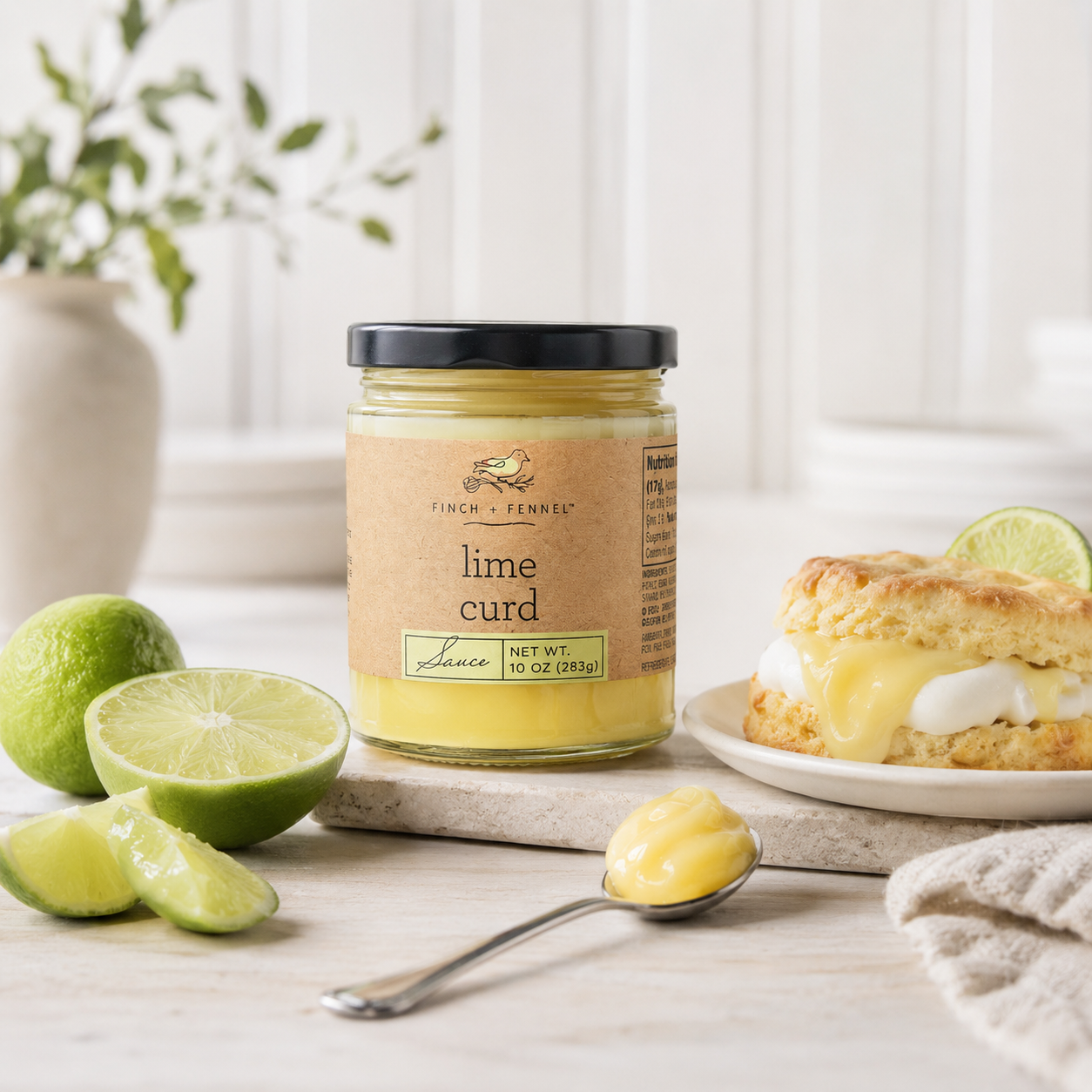 Jar of lime curd with limes and a scone on a wooden surface