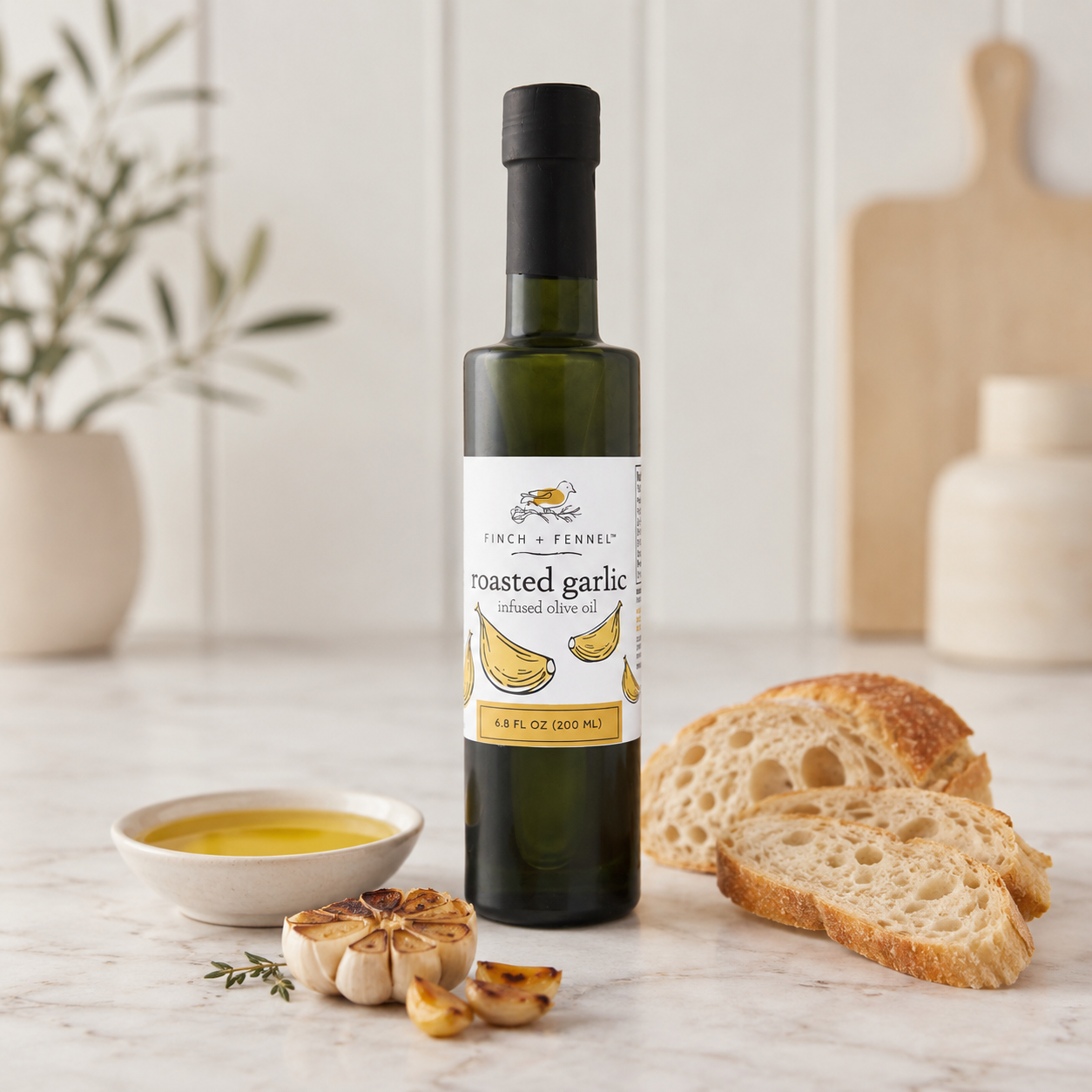 Bottle of roasted garlic olive oil on a table with bread and garlic bulbs.