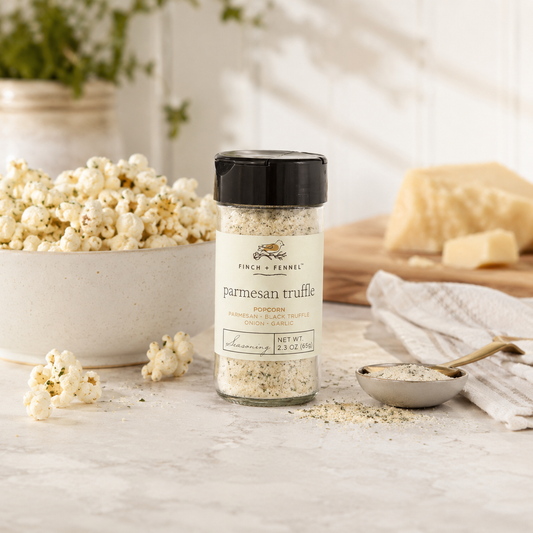 Jar of parmesan truffle seasoning on a table with popcorn and cheese in the background